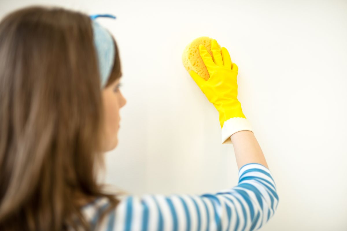 woman cleaning a rendered wall